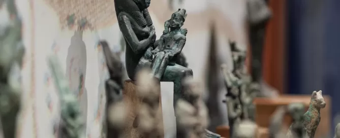 MAEC Cortona collezione egizia. Scultura in bronzo di Iside seduta con Horus sulle ginocchia, in atto di allattarlo, su base trapezoidale.