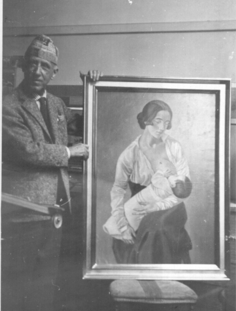 Fotografia in bianco e nero di Gino Severini accanto al dipinto Maternità. L'artista, in piedi, indossa una giacca, una cravatta e un berretto. Con una mano sostiene la cornice del quadro, che raffigura una giovane madre mentre allatta il proprio bambino. La scena è ambientata in uno spazio interno e documenta il legame tra Severini e una delle sue opere più celebri.