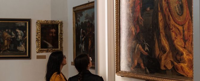 Due visitatrici osservano la Madonna in trono con Bambino e Santi di Pietro da Cortona esposta nelle sale del MAEC.