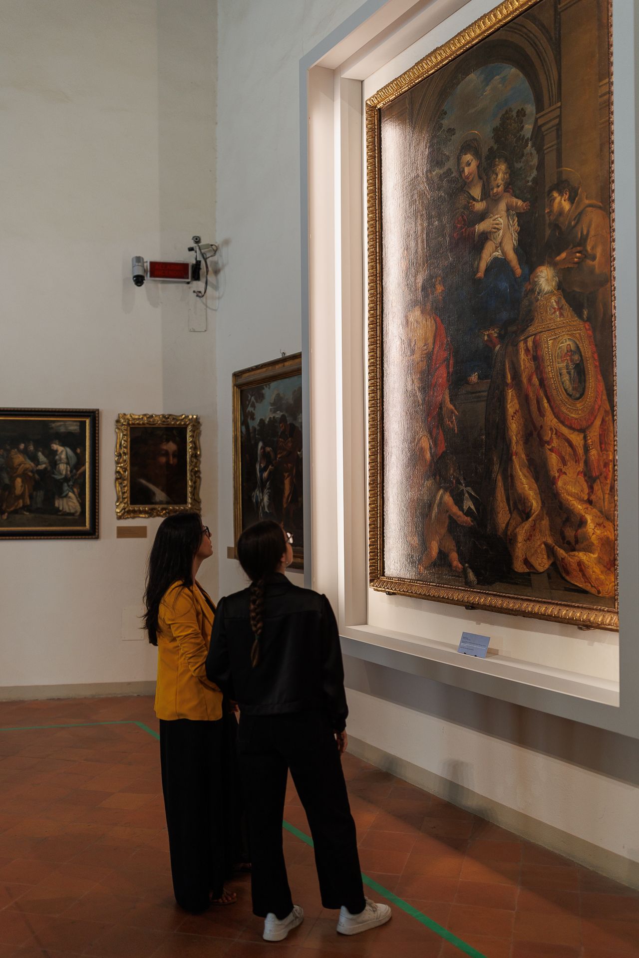 Madonna con Bambino di Pietro Berrettini Due visitatrici osservano la Madonna in trono con Bambino e Santi di Pietro da Cortona esposta nelle sale del MAEC.